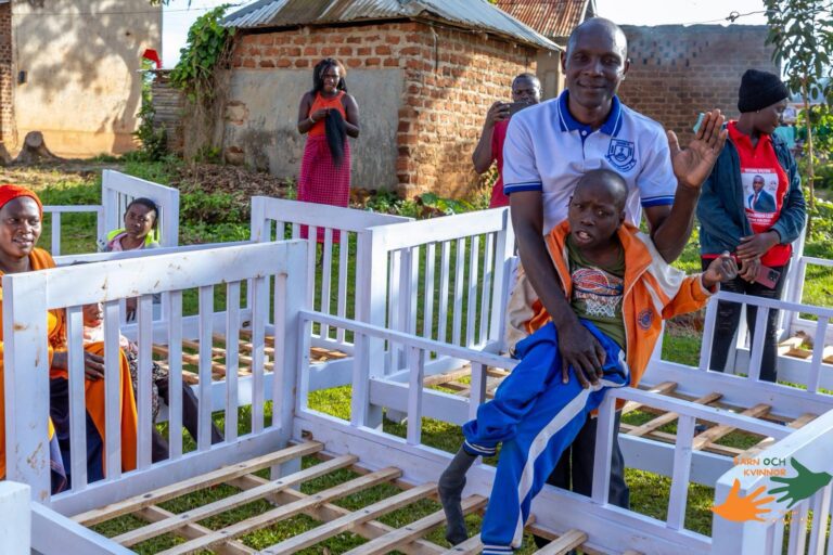 A father lifts his child in celebration after receiving a bed.