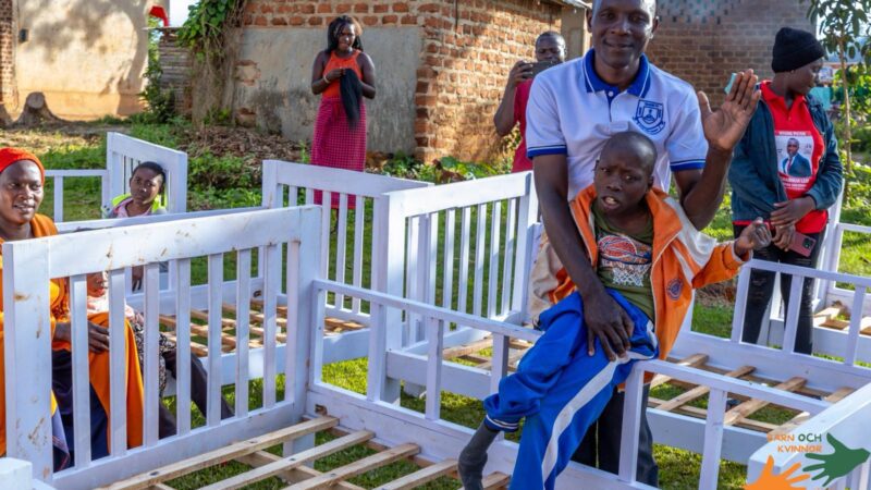 A father lifts his child in celebration after receiving a bed.