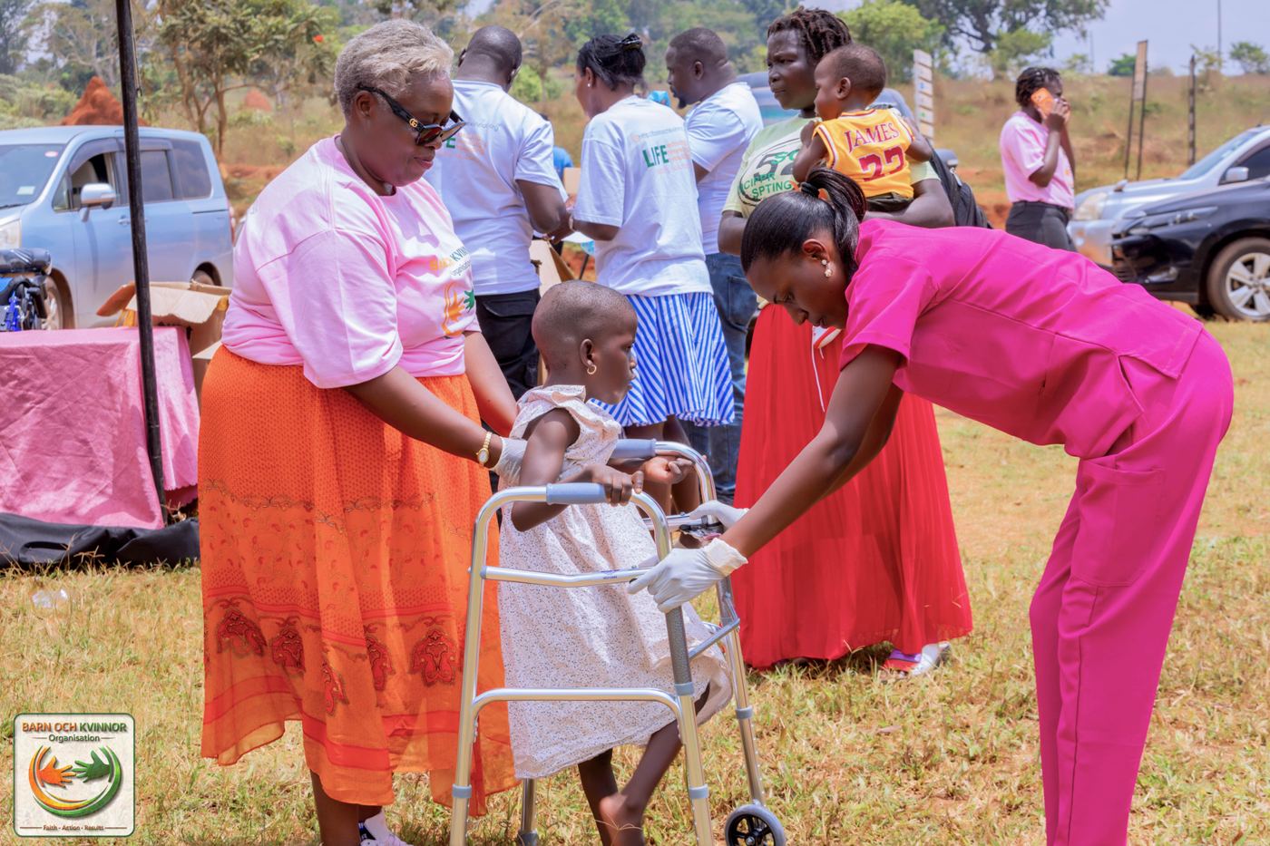 Caregivers and BOK staff help a child take her first steps in a walking frame.