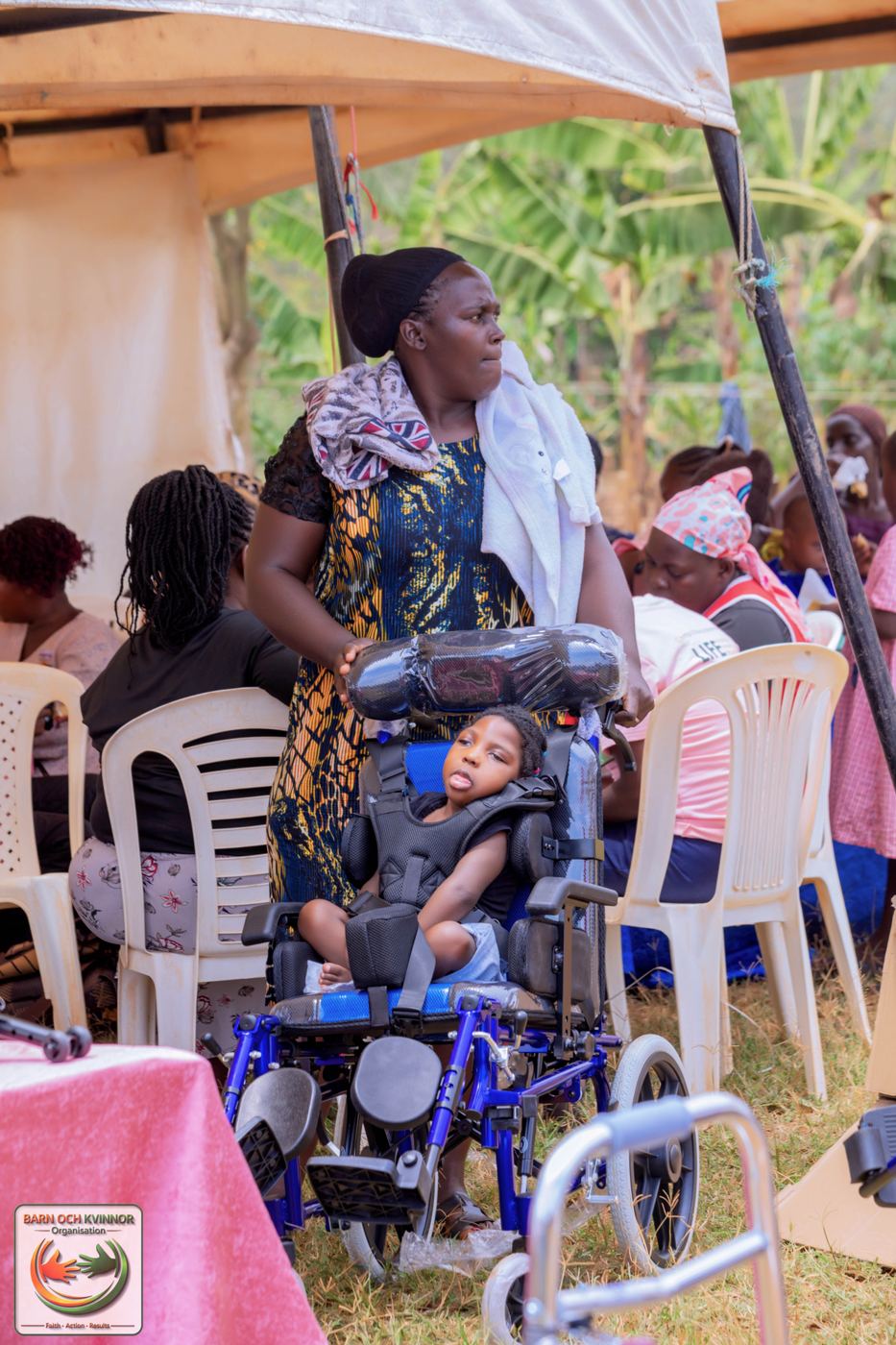 A child settles into a specially adapted wheelchair under the outreach tent.