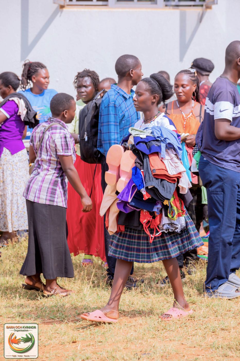 A young volunteer helps carry donated clothing and shoes.