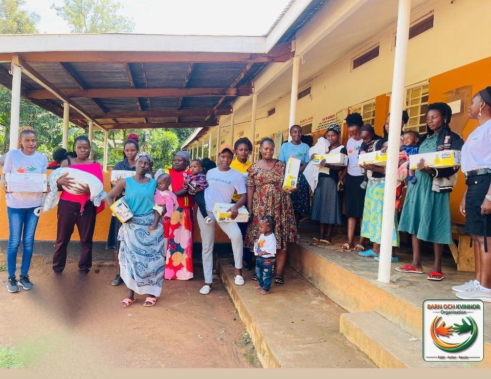 Mothers and the team gathered outside the health centre holding Mama Kits