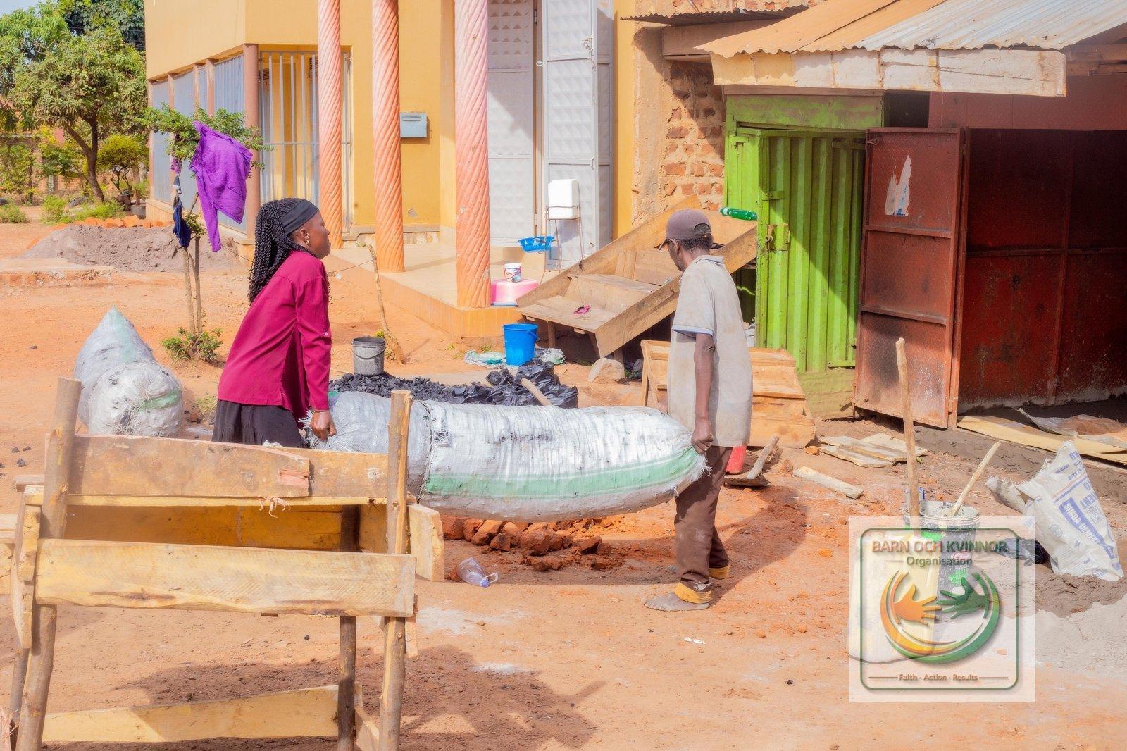 Mama Jennifer and a helper unloading charcoal at her stall