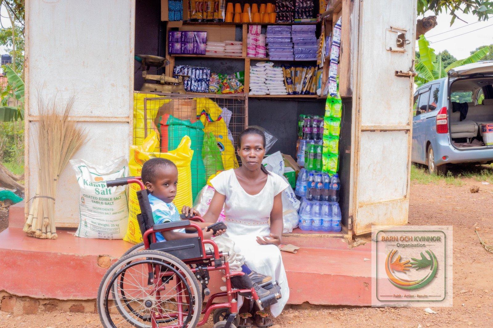 Agnes sitting at her kiosk with her son in his wheelchair