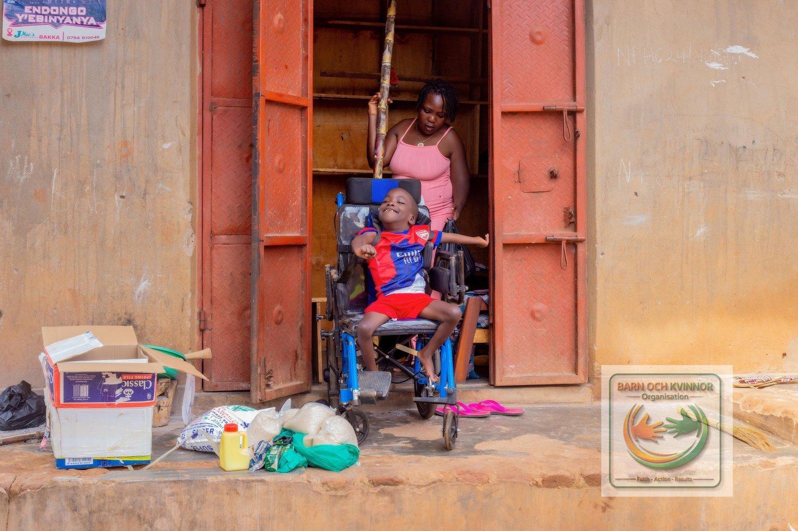 Mama Kato at her kiosk with her son in his wheelchair